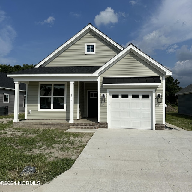 view of front of property with a garage, central air condition unit, and covered porch