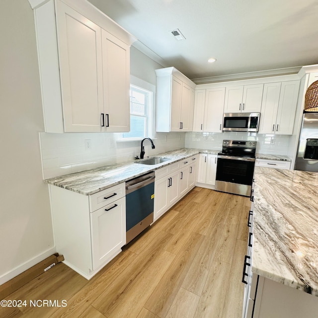 kitchen with decorative backsplash, light hardwood / wood-style flooring, appliances with stainless steel finishes, and white cabinets