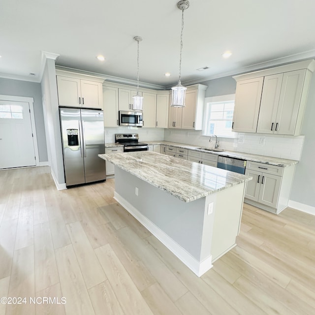 kitchen with stainless steel appliances, sink, light stone countertops, a kitchen island, and light hardwood / wood-style floors