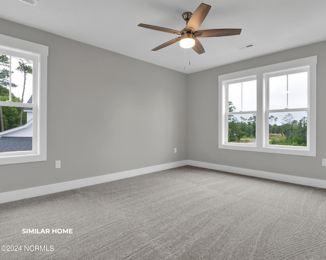 carpeted spare room with a ceiling fan, visible vents, and baseboards