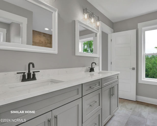 bathroom featuring double vanity, a sink, and a healthy amount of sunlight