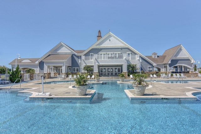 back of house featuring a patio, a chimney, and a community pool