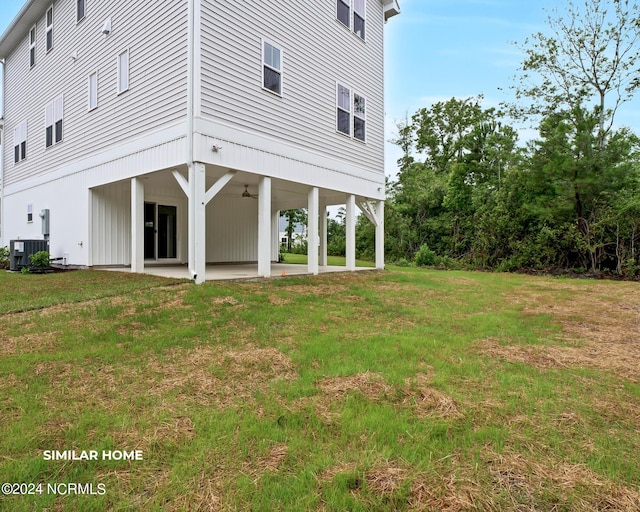 rear view of property with central air condition unit, ceiling fan, a lawn, and a patio