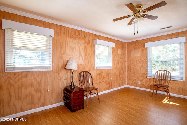 sitting room featuring light hardwood / wood-style floors, ceiling fan, a wealth of natural light, and ornamental molding