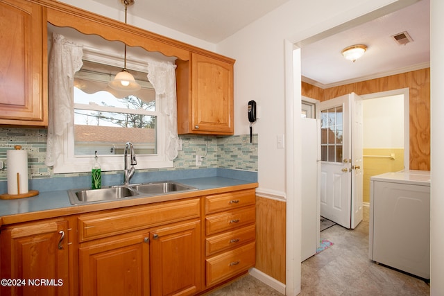 kitchen with hanging light fixtures, backsplash, light tile floors, sink, and washer / clothes dryer