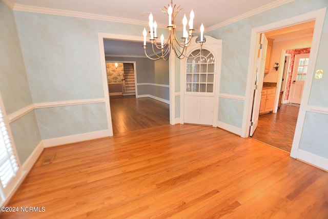 unfurnished dining area with crown molding, a notable chandelier, and wood-type flooring