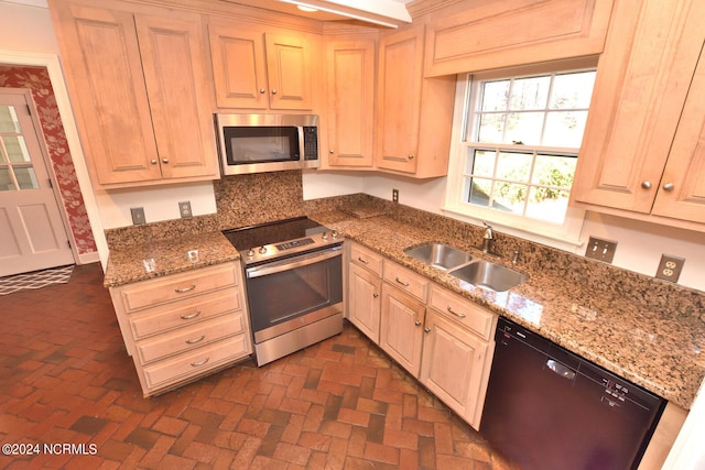 kitchen featuring backsplash, dark stone counters, appliances with stainless steel finishes, and sink