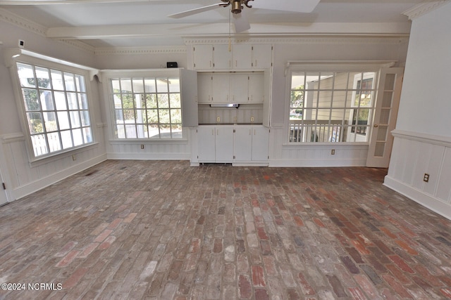 unfurnished living room with beam ceiling, ceiling fan, and a healthy amount of sunlight