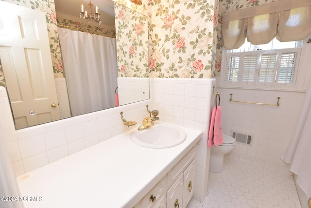 bathroom with tile walls, an inviting chandelier, tile floors, toilet, and large vanity