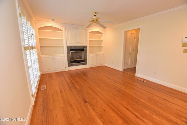 unfurnished living room with crown molding, light hardwood / wood-style floors, ceiling fan, and a tile fireplace