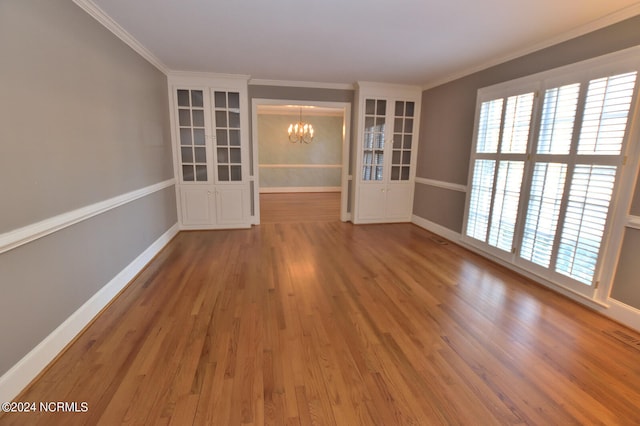 unfurnished room featuring light hardwood / wood-style flooring, a notable chandelier, and crown molding