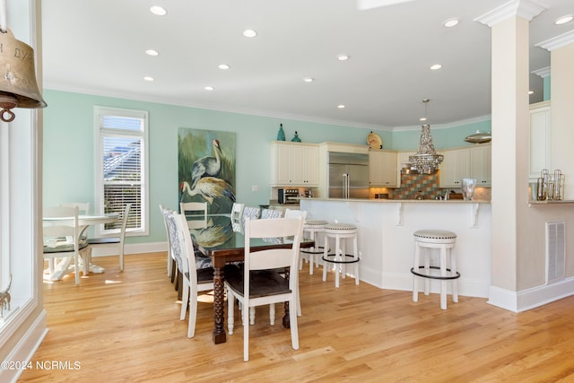 dining area featuring ornamental molding and light hardwood / wood-style flooring