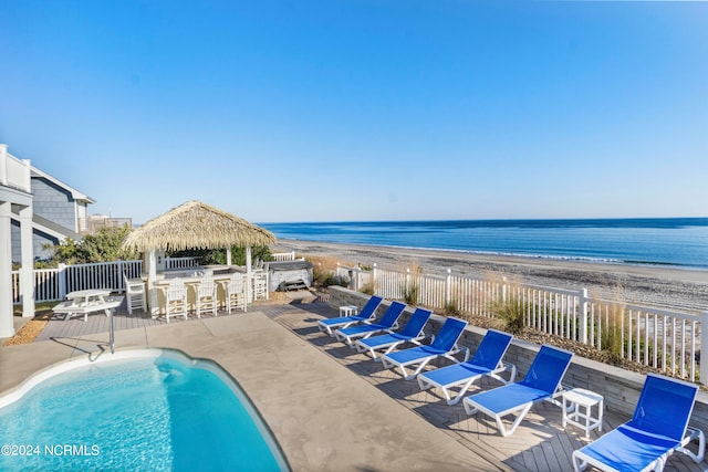 view of swimming pool featuring a patio area, a beach view, a gazebo, and a water view