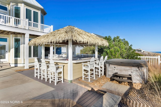 wooden terrace with exterior bar, a gazebo, a patio area, and a hot tub