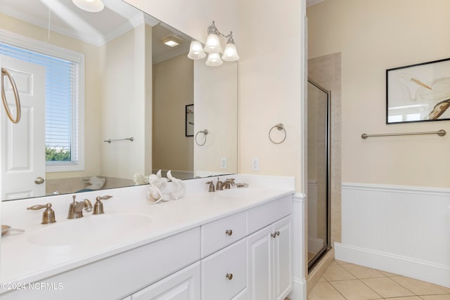 bathroom featuring a shower with shower door, crown molding, double sink vanity, and tile floors