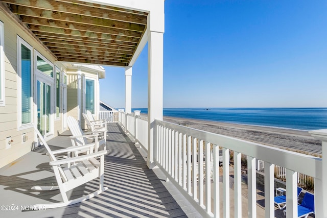 balcony with a water view and a view of the beach