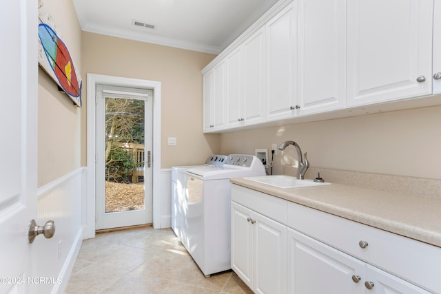 clothes washing area featuring washer hookup, cabinets, washing machine and clothes dryer, crown molding, and sink