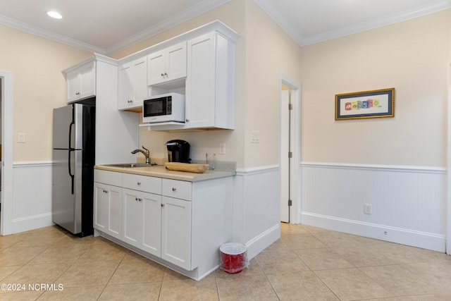 kitchen featuring white cabinetry, light tile flooring, sink, crown molding, and stainless steel refrigerator