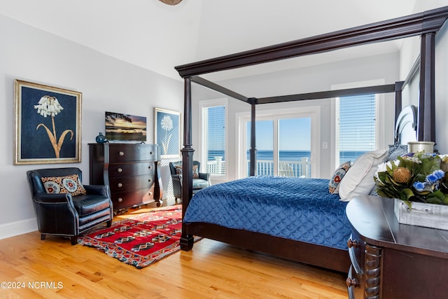 bedroom with light hardwood / wood-style floors, access to outside, and a water view