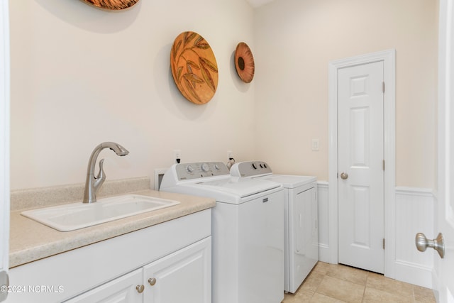 clothes washing area featuring washer and dryer, light tile floors, cabinets, and sink