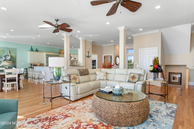 living room featuring light hardwood / wood-style floors, ceiling fan, decorative columns, and ornamental molding