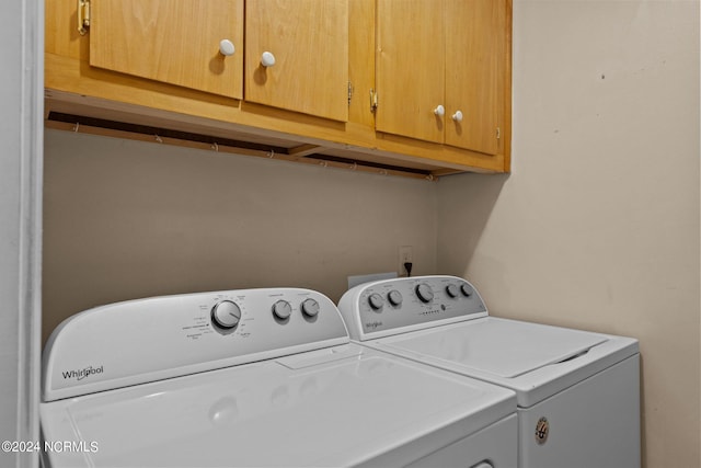 laundry room featuring separate washer and dryer and cabinets