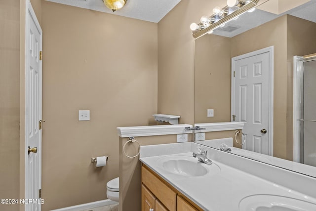 bathroom with a textured ceiling, double sink, toilet, and vanity with extensive cabinet space