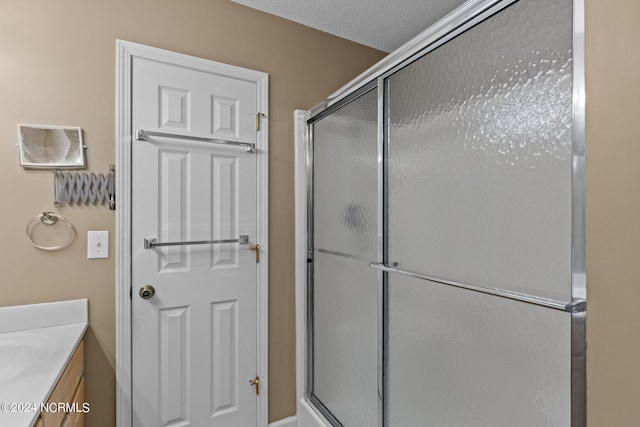 bathroom with a textured ceiling, vanity, and a shower with shower door