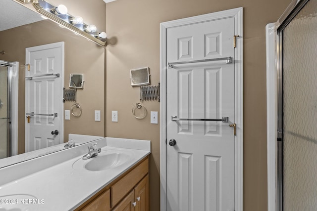 bathroom featuring double sink, oversized vanity, and a shower with door