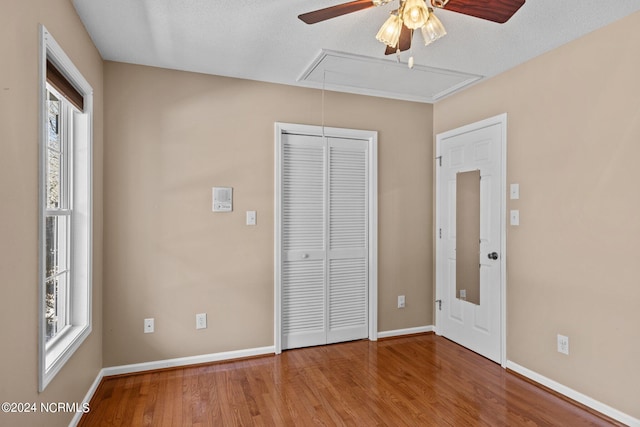 unfurnished bedroom with dark hardwood / wood-style flooring, ceiling fan, multiple windows, and a closet