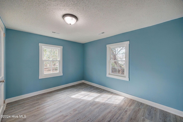 empty room featuring a textured ceiling and hardwood / wood-style flooring