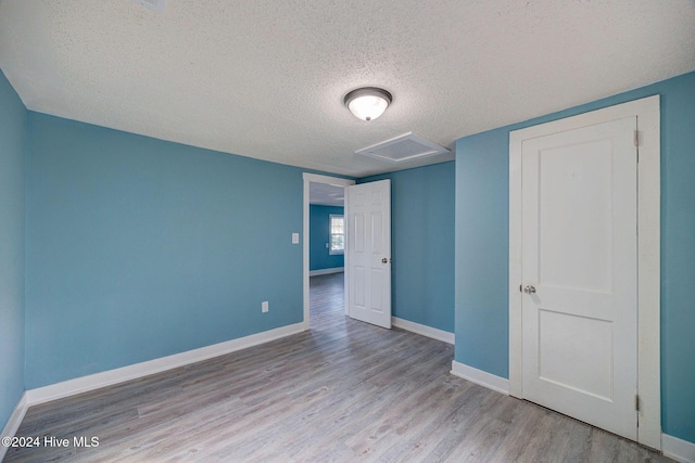 spare room with light hardwood / wood-style floors and a textured ceiling