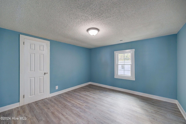 unfurnished room featuring hardwood / wood-style flooring and a textured ceiling