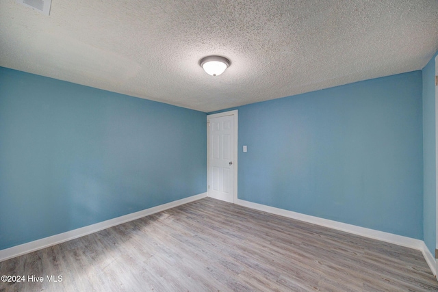 unfurnished room featuring wood-type flooring and a textured ceiling