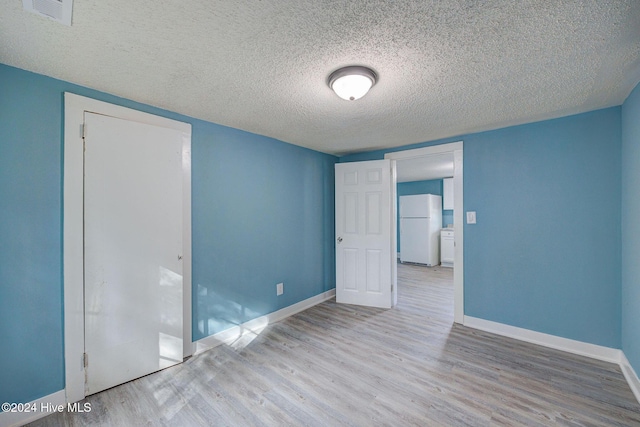 spare room featuring light wood-type flooring and a textured ceiling