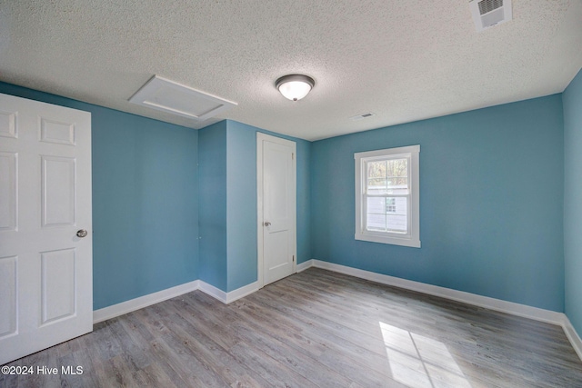 unfurnished room with a textured ceiling and light hardwood / wood-style floors