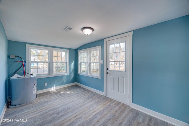 entryway featuring light hardwood / wood-style floors, lofted ceiling, and water heater