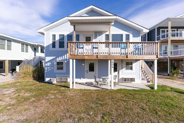 rear view of property featuring a deck, a lawn, and a patio area