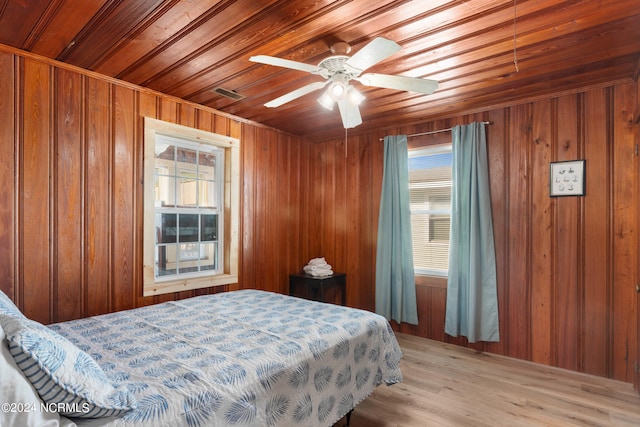 bedroom with wooden walls, light hardwood / wood-style flooring, wooden ceiling, and multiple windows