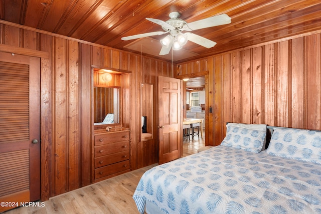 bedroom featuring light hardwood / wood-style floors, wood ceiling, wooden walls, and ceiling fan