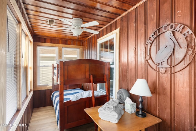 bedroom with wooden walls, ceiling fan, and light wood-type flooring