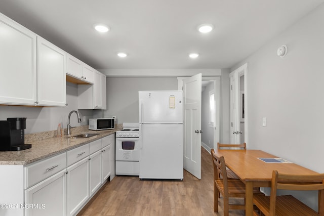 kitchen featuring white appliances, sink, light stone counters, light hardwood / wood-style floors, and white cabinetry