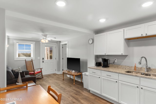 kitchen with white cabinetry, ceiling fan, light hardwood / wood-style floors, sink, and light stone counters