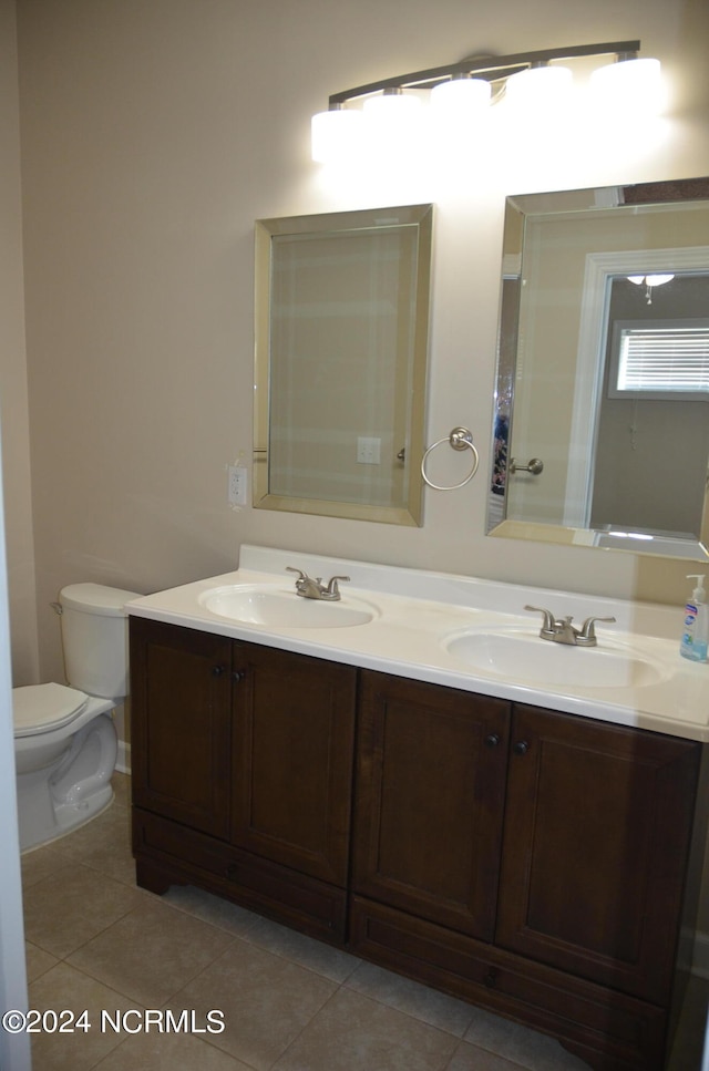 bathroom with double sink vanity, toilet, and tile floors