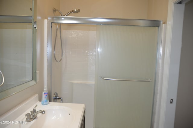 bathroom with a shower with shower door and large vanity