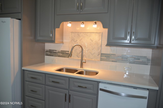 kitchen featuring gray cabinetry, sink, white appliances, and backsplash