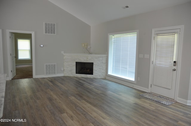 unfurnished living room with a stone fireplace, high vaulted ceiling, and dark wood-type flooring