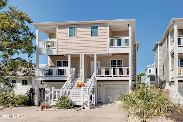 coastal home with a porch, a balcony, and a garage