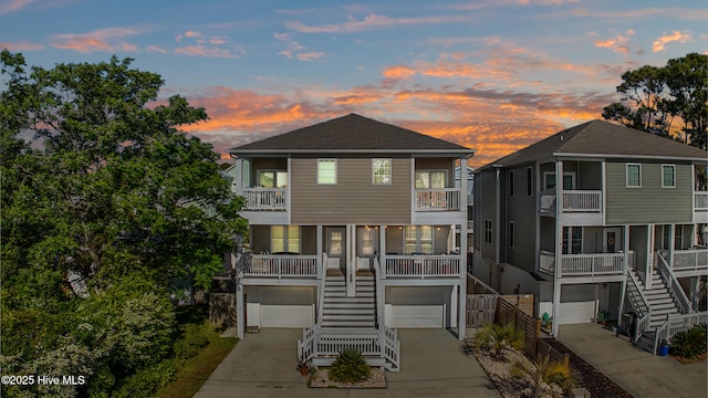 view of front of home featuring driveway, a garage, a balcony, a shingled roof, and stairs