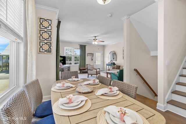 dining space with baseboards, ceiling fan, wood finished floors, and stairway